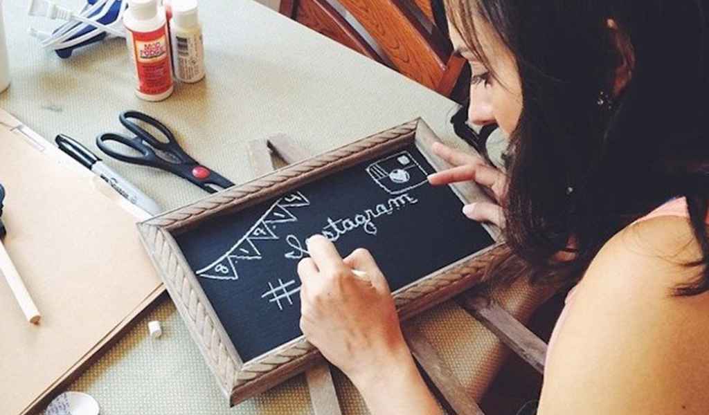 Nevesta piše s kredo na tablico napis, da bo njuna poroka brez telefonov. Foto: Moetic Wedding Films