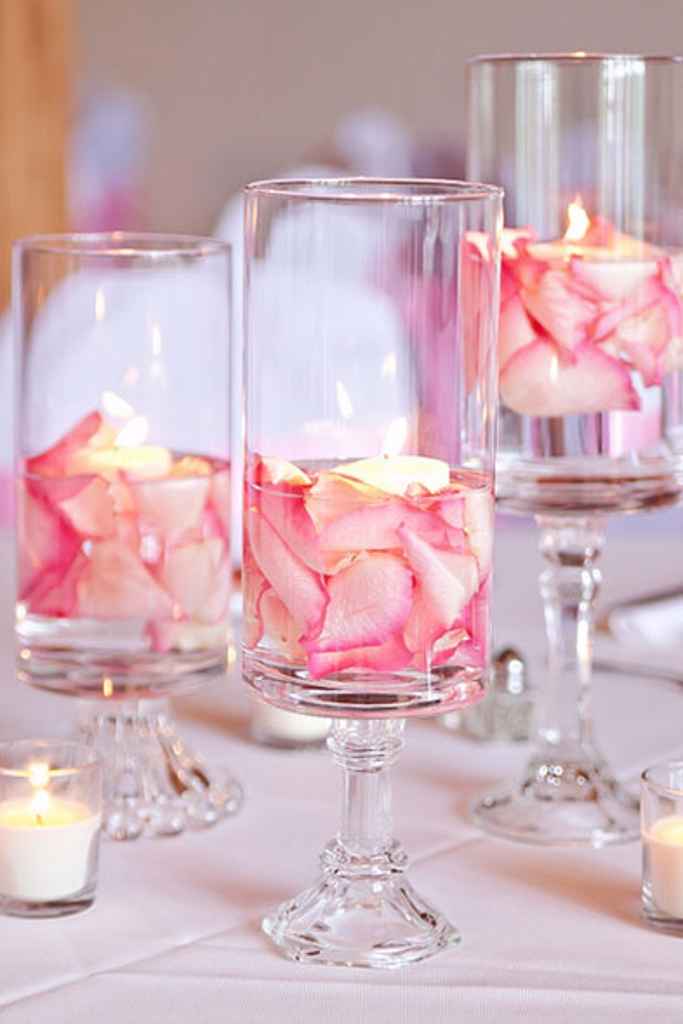 Preprosta poročna dekoracija v treh vazah v katerih so roza cvetlični lističi in svečke. Foto: Anya Albonetti