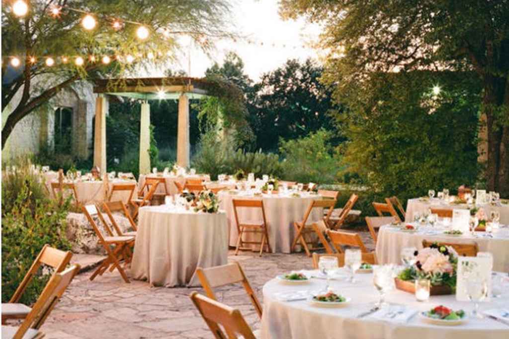 Elegantno romantična poroka v vrtu vile, ki je sestavljena iz okroglih miz in vrtnih lučk. Foto: Suzi Q | SMP