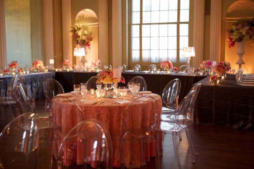 Postavitev čudovitega poročnega omizja v restavraciji s črnimi in roza prti, ter cvetlično dekoracijo in svečami. Ob mizah so postavljeni prozorni stoli, ki naredijo piko na i sami poročni dekoraciji. Foto: Storija weddings