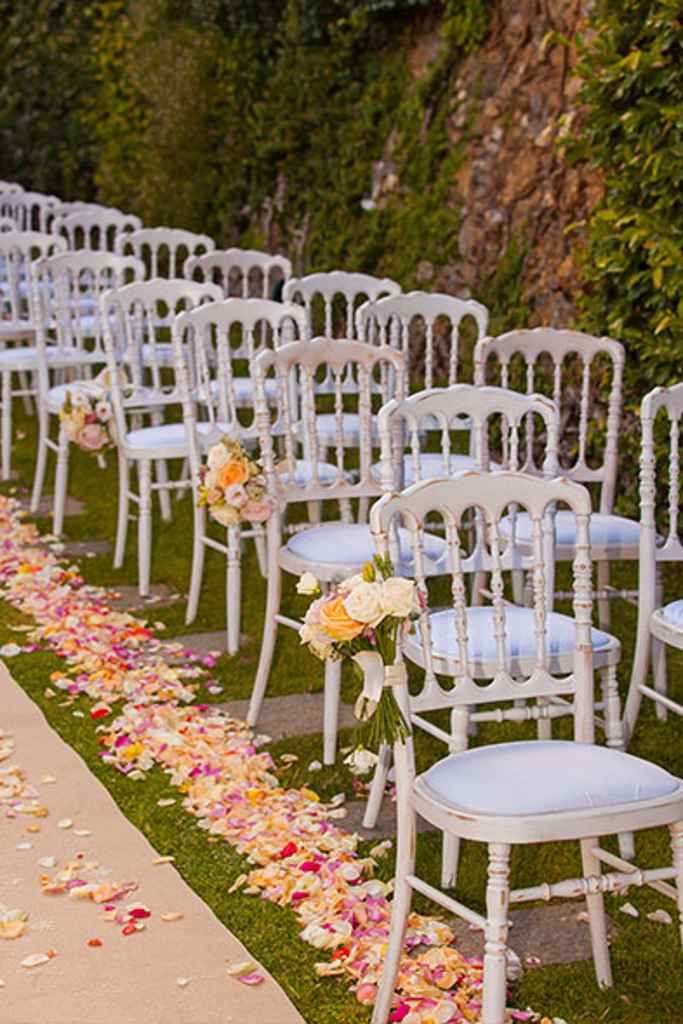 Ob belih stolih je na tleh posuto sveže cvetje v različnih barvah na civilnem obredu. Foto: Storija weddings
