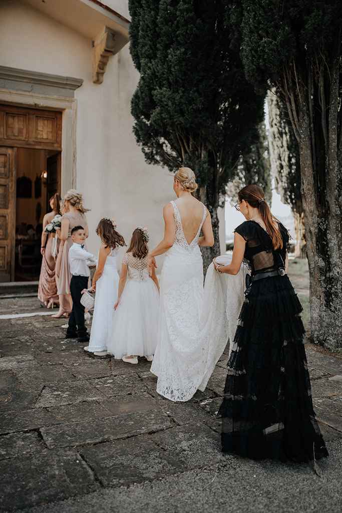 Poročna organizatorka Petra Starbek pomaga nevesti s poročno obleko, ko vstopa v cerkev. Foto: Ana Gregorič Photography