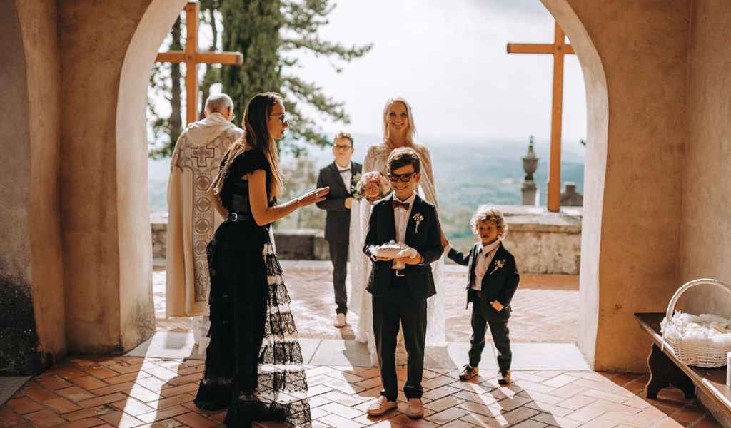 Organizatorka porok Petra Starbek postavlja poročni sprevod neveste in njenih pomočnikov za slovesni vhod v cerkev. Foto: Tamara Vidmar Photography