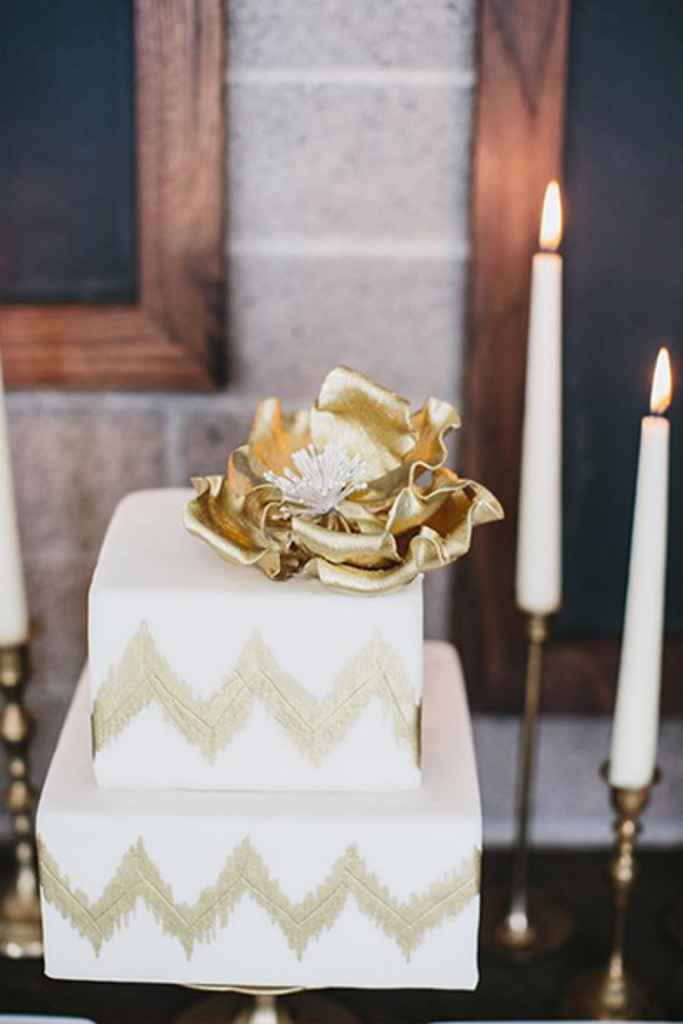 Bela dvonadstropna poročna torta z zlatim cvetom in zlatim cikcak vzorcem. Foto: Aaron Young
