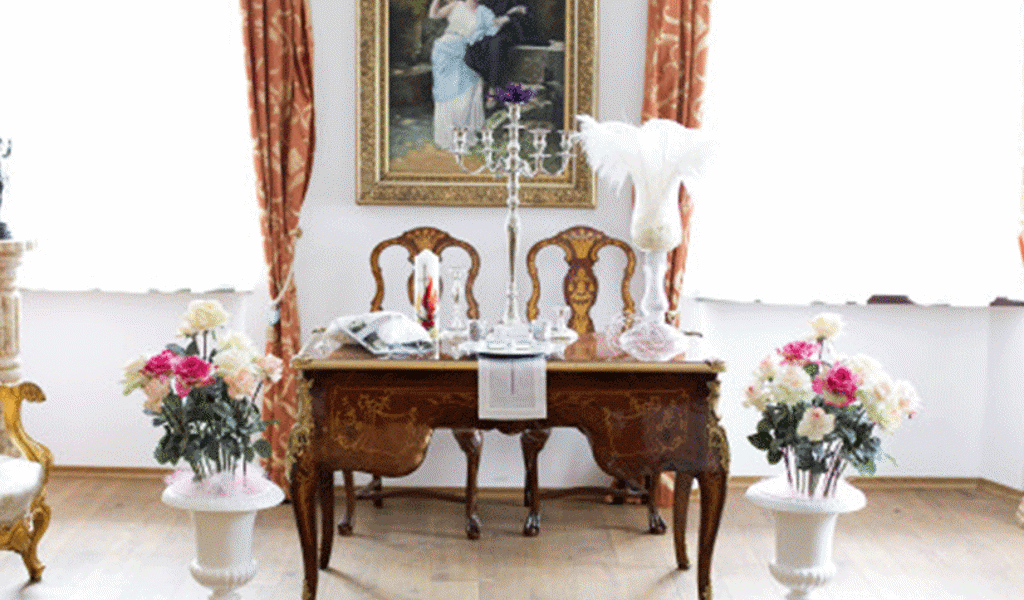 Postavitev poročne dekoracije (bele vaze, svečniki, srebrni pod-krožniki...) v dvorcu Rus v Lukovici. Foto: Storija weddings