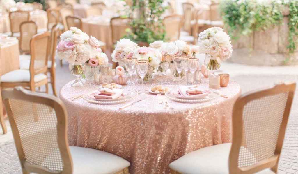 Romantično poročno omizje z zlatim prtom, svetlo roza cvetličnimi aranžmaji ter dodatki v roza barvi. Foto: Sandra Åberg Photography 