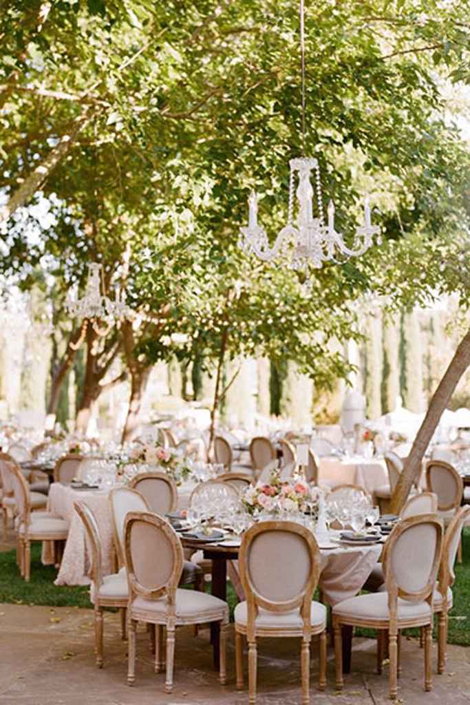Domač vrt lahko postane prekrasna poročna lokacija, če postavimo okrogle mize s prekrasnim cvetličnim aranžmajem v zlatih baročnih vazah, najamemo prekrasne lesene stole iz Hiše vizij ter dodamo lestence na drevo. Foto: Sylvie Gil Photography