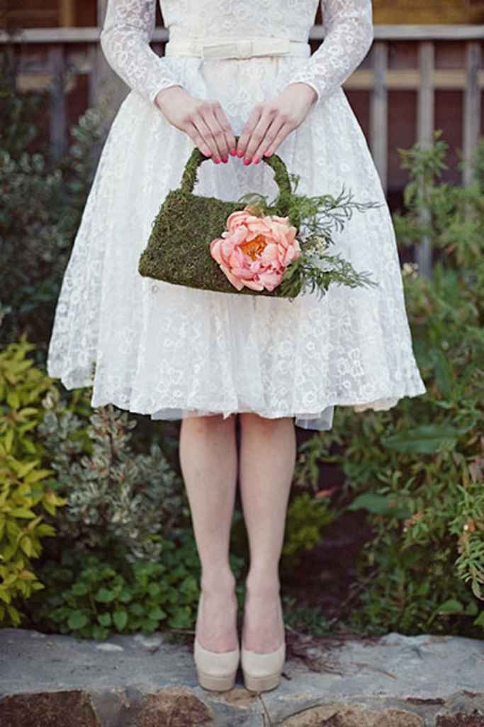 Nevesta v kratki poročni obleki drži poročni šopek v obliki torbice iz mahu in velikega roza cveta. Foto: Two Spoons Photography