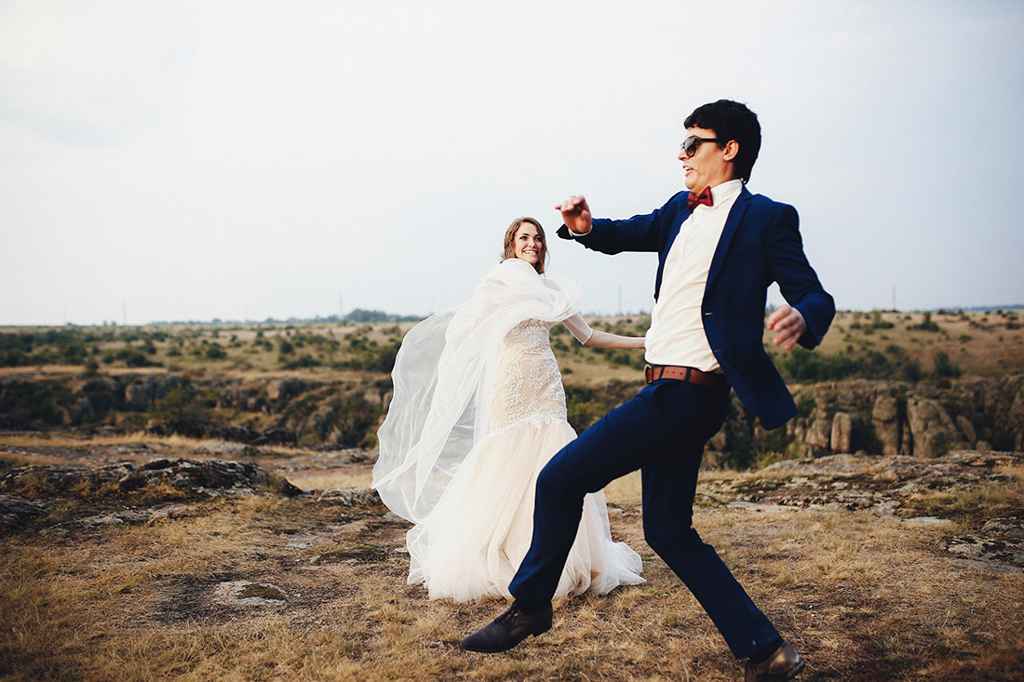 Nevesta in ženin se zabavata med poročnim fotografiranjem v hribih. Foto: Storija weddings