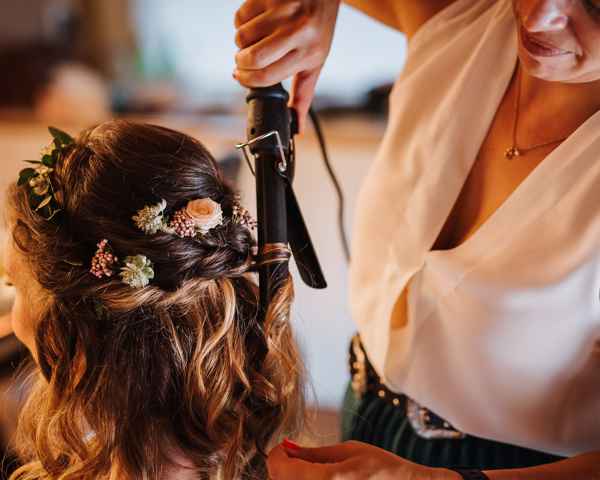 Frizerka in vizažistka Sandra iz Sfumato makeup zaključuje poročno frizuro. V laseh ima nevesta vpeto tudi cvetje.