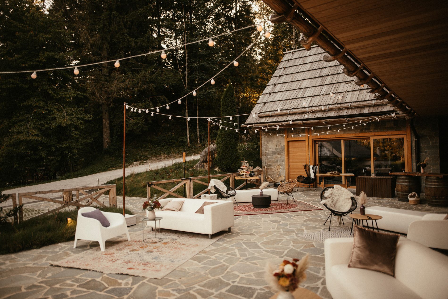 Ena izmed najlepših poročnih lokacij na gorenjskem, Vila Planinka. Na terasi stojijo vrne luči, sedežne garniture, unikatni stoli, cvetje ter akrilne table s kaligrafskimi napisi. Vsa dekoracija je v temi boho poroke, za katero je poskrbela edinstvena Petra Starbek.